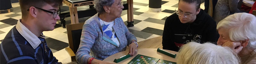 Students playing board games with elderly people at a nursing home